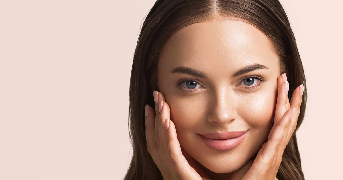 Woman showing her glowing, youthful skin holding her face gently after facial rejuvenation in Aldie, VA.